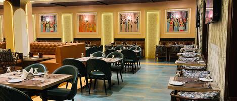 A restaurant with a long counter, multiple tables, and chairs.