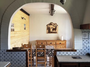 Eine rustikale Küche mit Holzschränken, einem Esstisch mit Stühlen und einem an der Wand befestigten Holzbild.