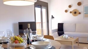 A dining area with a table set for two, a television, and a sofa in the background. - Sunny Apartment for 4 in Vera (Arona)