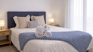 A neatly made bed with rolled towels, a blue knitted blanket, and a headboard. - Sunny Apartment for 4 in Vera (Arona)