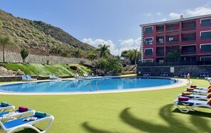 A swimming pool with lounge chairs and a building with balconies. - Sunny Apartment for 4 in Vera (Arona)