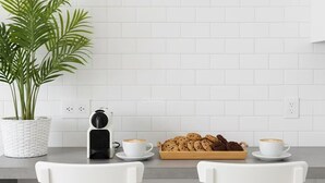 A modern kitchen with white tiled walls, a potted plant, a coffee maker, two cups of coffee, and a tray of cookies. - Sunny Apartment for 4 in Vera (Arona)