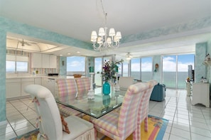 A spacious kitchen with a glass dining table, white chairs, and a view of the ocean. - Colorful Coastal Retreat ST 2096 w/Beach Service (Destin)