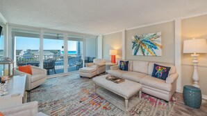 Un salon spacieux avec une grande fenêtre, un tapis coloré et une vue sur l’océan.