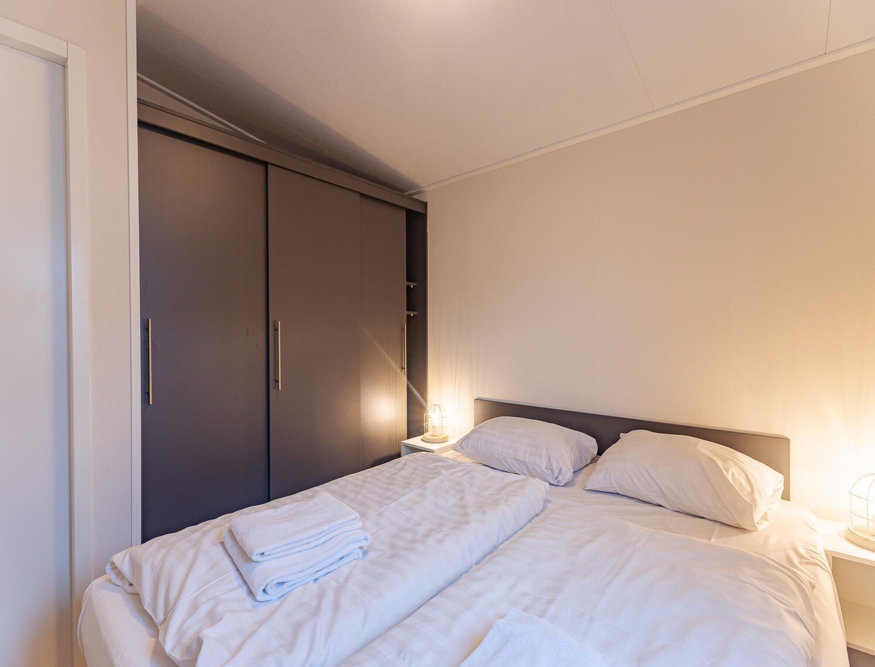 A hotel room with a bed, a wardrobe, and a nightstand.