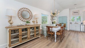 Un coin repas avec un buffet en bois, un lustre et un grand miroir rond accroché au mur.