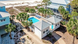Une propriété située en bord de mer, dotée d’une piscine, de palmiers et offrant une vue sur l’océan.