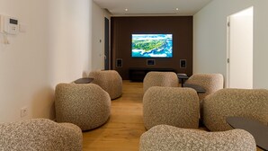 Ein moderner Loungebereich mit runden, strukturierten Sitzgelegenheiten und einem großen Flachbildfernseher an der Wand.