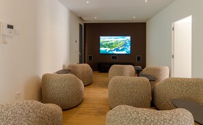 Ein moderner Loungebereich mit runden, strukturierten Sitzgelegenheiten und einem großen Flachbildfernseher an der Wand.