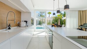 Eine moderne Küche mit einer großen Kochinsel, einem Einbauofen und Blick auf einen Pool.