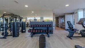 Un gimnasio con equipo de levantamiento de pesas, cintas de correr y bancos.