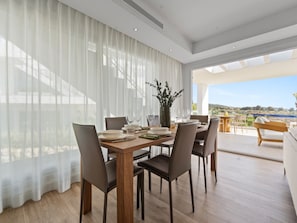 A dining area with a wooden table, chairs, and a view of the outdoors. - Spacious Apartment for 4 With Solarium (Casares)