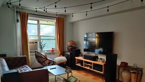 Una sala de estar con sofá, mesa de centro, televisor y estantería.