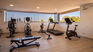 A modern gym with various exercise equipment, large windows, and a wooden floor. - Exclusive 3-bed Penthouse Alcazaba Lagoon (Casares)