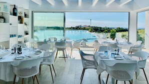 A modern dining area with tables set for a meal, overlooking a pool and a scenic view. - Exclusive 3-bed Penthouse Alcazaba Lagoon (Casares)