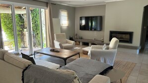 En moderne stue med sofa, lænestole, sofabord, et fladskærms-tv og pejs.