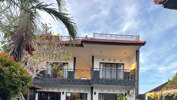 A two-story house with a balcony, a swimming pool, and various plants. - Q-Star Uluwatu (Ungasan)
