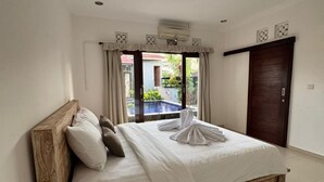 A bedroom with a wooden bed, white linens, a view of a swimming pool, and a dark wooden door. - Q-Star Uluwatu (Ungasan)