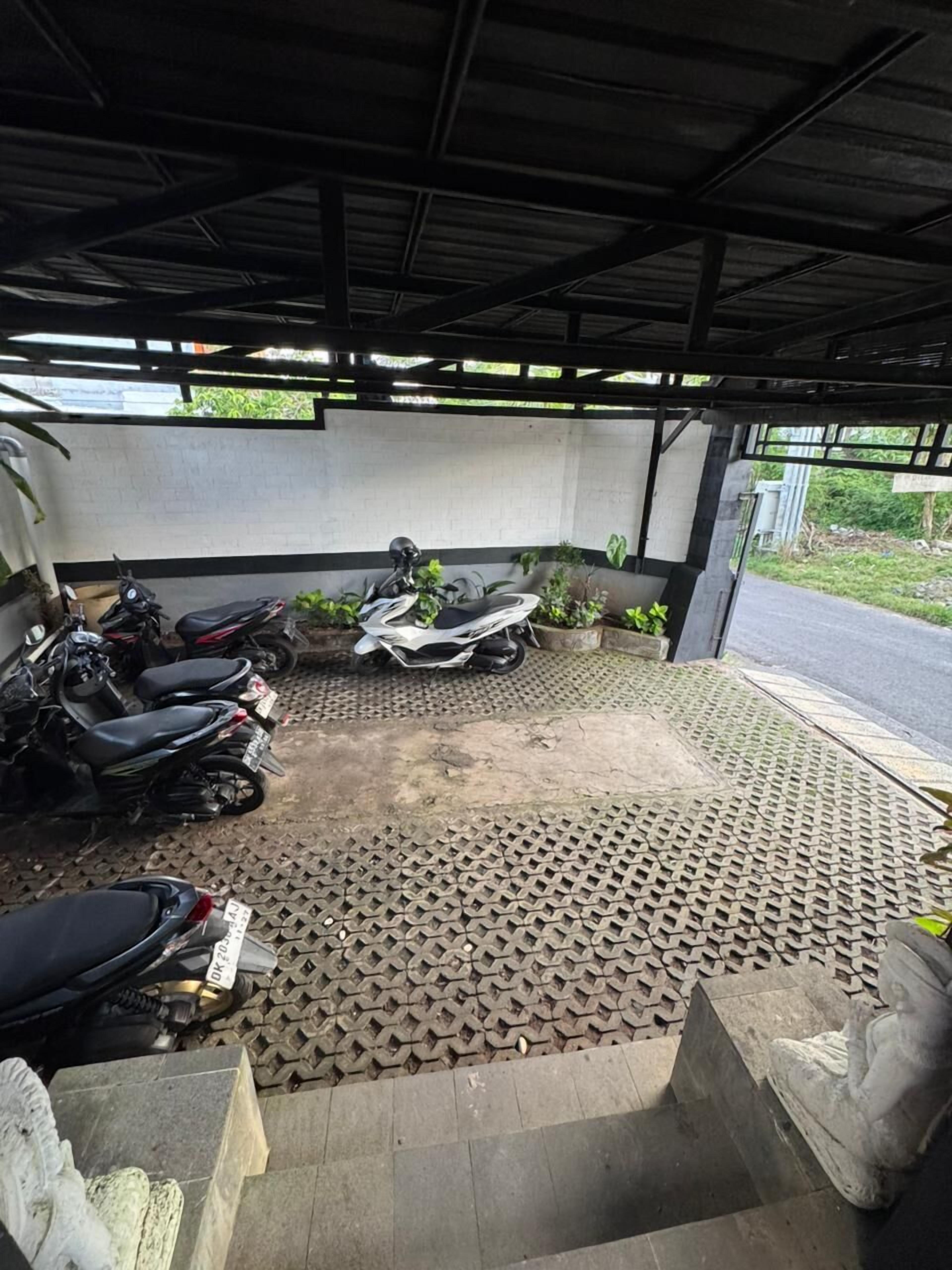 A covered parking area with several motorcycles parked.
