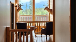 Un interior de madera con una araña, un balcón con vistas y una escalera.