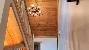 Una escalera de madera con barandilla, un candelabro y una lámpara fijada a la pared.