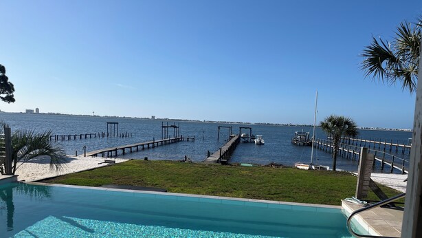 A clear view of a swimming pool with a wooden deck and a dock extending into the water.