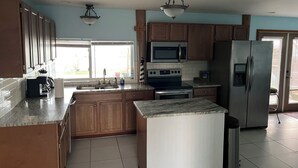 A kitchen with wooden cabinets, a stainless steel refrigerator, a microwave, an oven, and a sink.