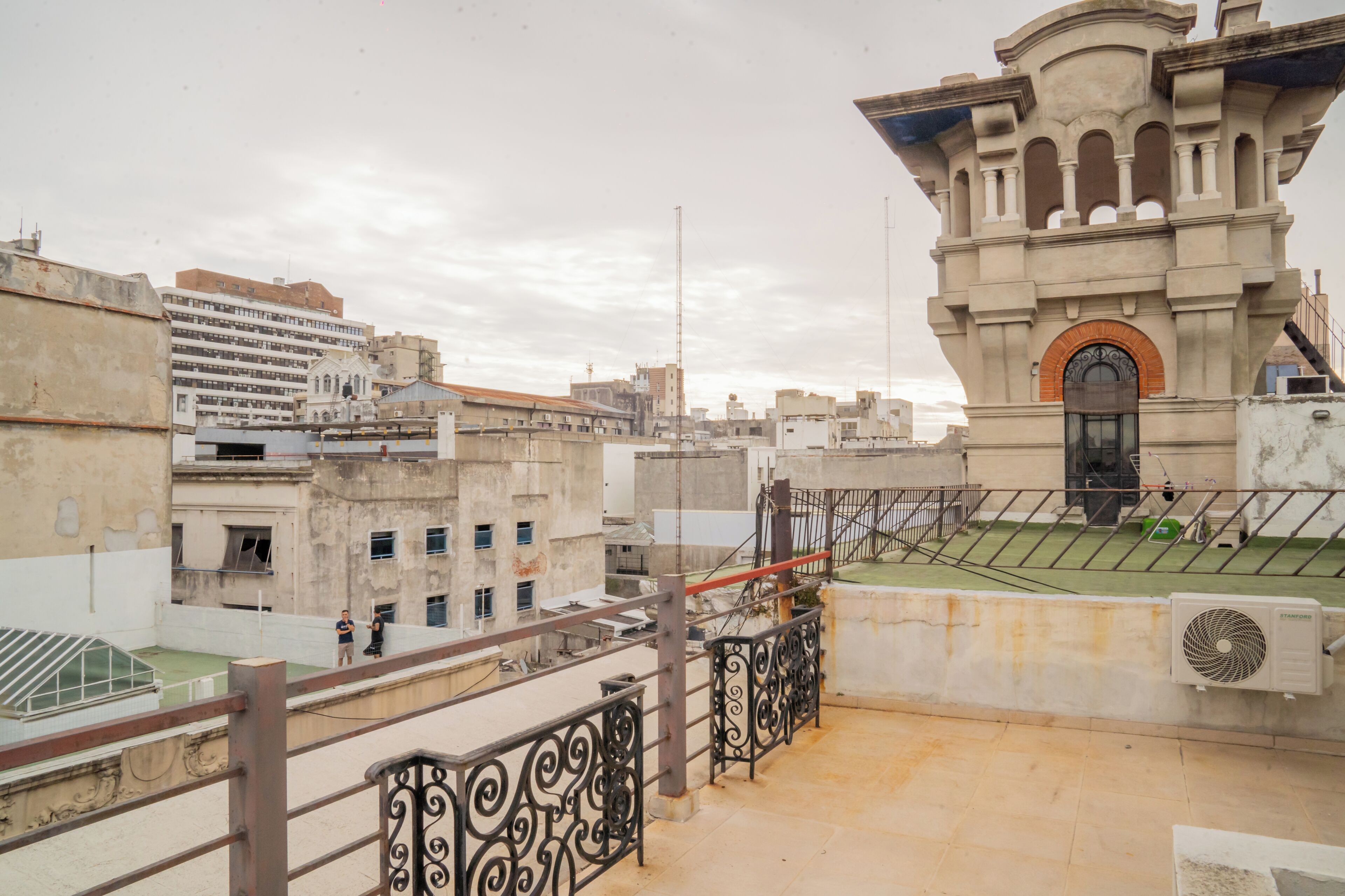 A rooftop terrace with a view of a historic building, a staircase, and a flagpole.