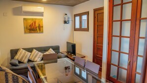 A living room with a glass-top coffee table, a sofa with patterned cushions, a television, and a painting on the wall. - Penthouse with two terraces at the Old City [502]. (Montevideo)