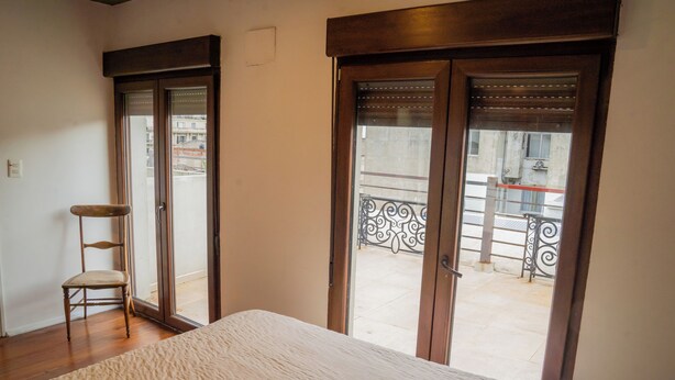A bedroom with a large bed, a chair, and a balcony with a metal railing. - Penthouse with two terraces at the Old City [502]. (Montevideo)