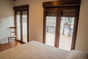 Ein Schlafzimmer mit einem großen Bett, einem Sessel und einem Balkon mit Metallgeländer.