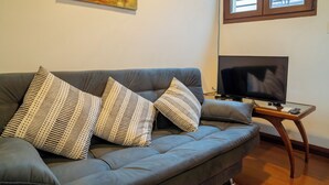 A living room with a grey sofa, patterned cushions, a flat-screen TV on a wooden stand, and a painting on the wall. - Penthouse with two terraces at the Old City [502]. (Montevideo)