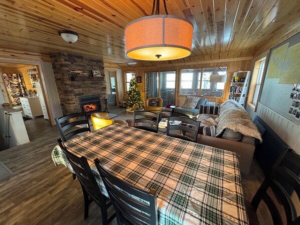 Interior acogedor de una cabaña con comedor, chimenea y un árbol de Navidad.
