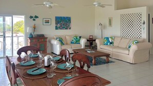 Un salón amplio con techo alto, una mesa de comedor lista para cuatro personas y dos sofás.