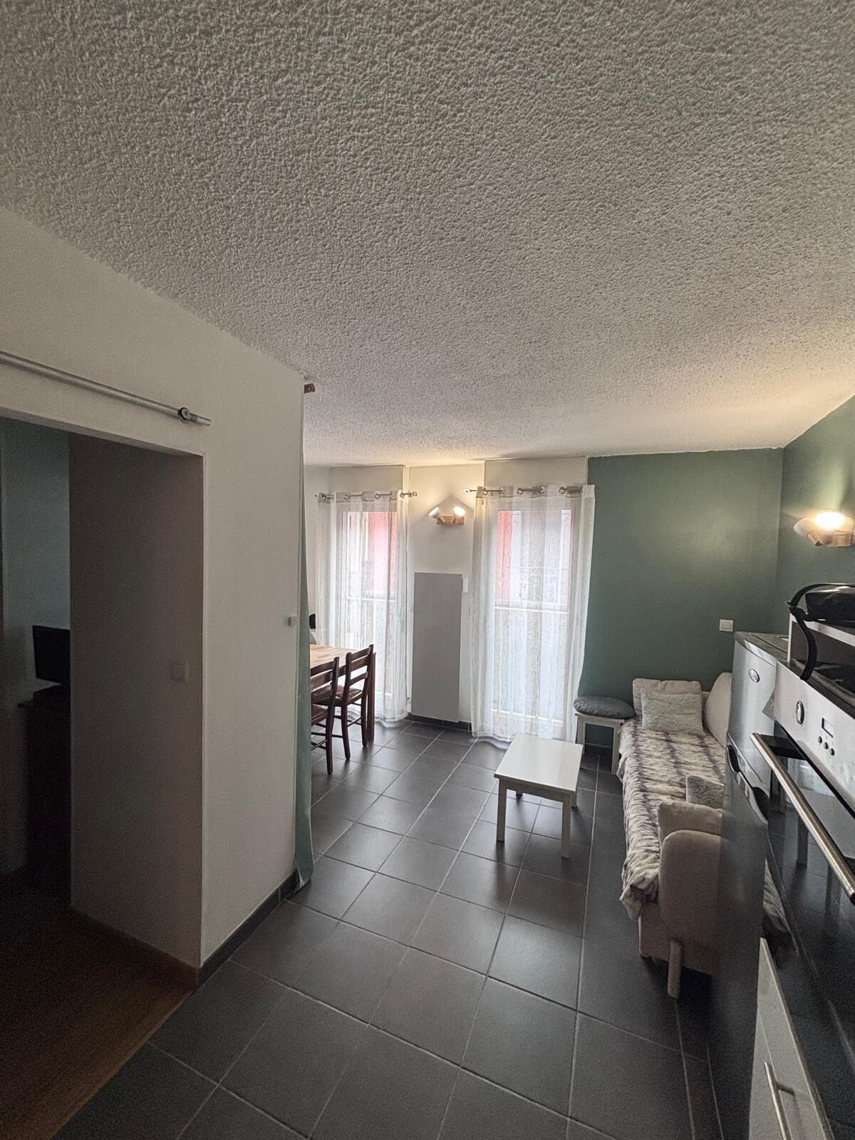 Een knus woongedeelte met kitchenette, eethoek en zithoek met een bank en een kleine tafel.