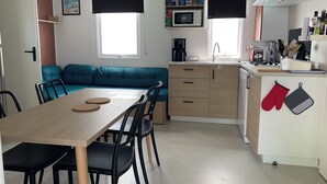 Una cocina compacta con comedor, un sofá color turquesa y un refrigerador pequeño.