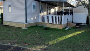 Una casa móvil con porche y una terraza cercada.