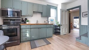 Una cocina moderna con armarios azul claro, electrodomésticos de acero inoxidable y encimera de madera.