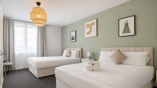 Ein Hotelzimmer mit zwei Betten, einer Sitzecke und einem großen Fenster mit Vorhängen.
