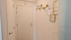 Una porta blanca amb un pom, una làmpada subjecta a la paret i una presa elèctrica.