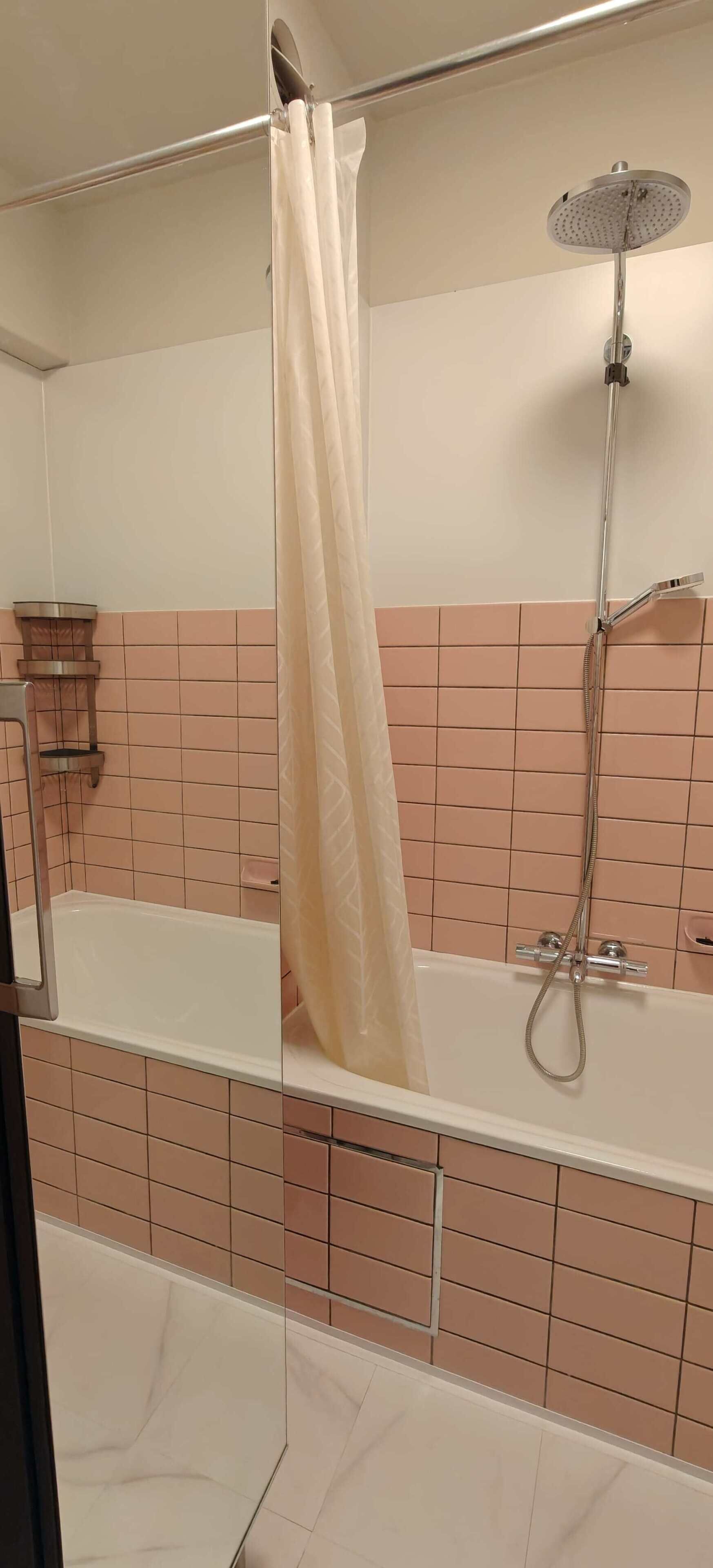 Suihkutila, jossa on lasiseinä, käsisuihku ja kylpyamme.