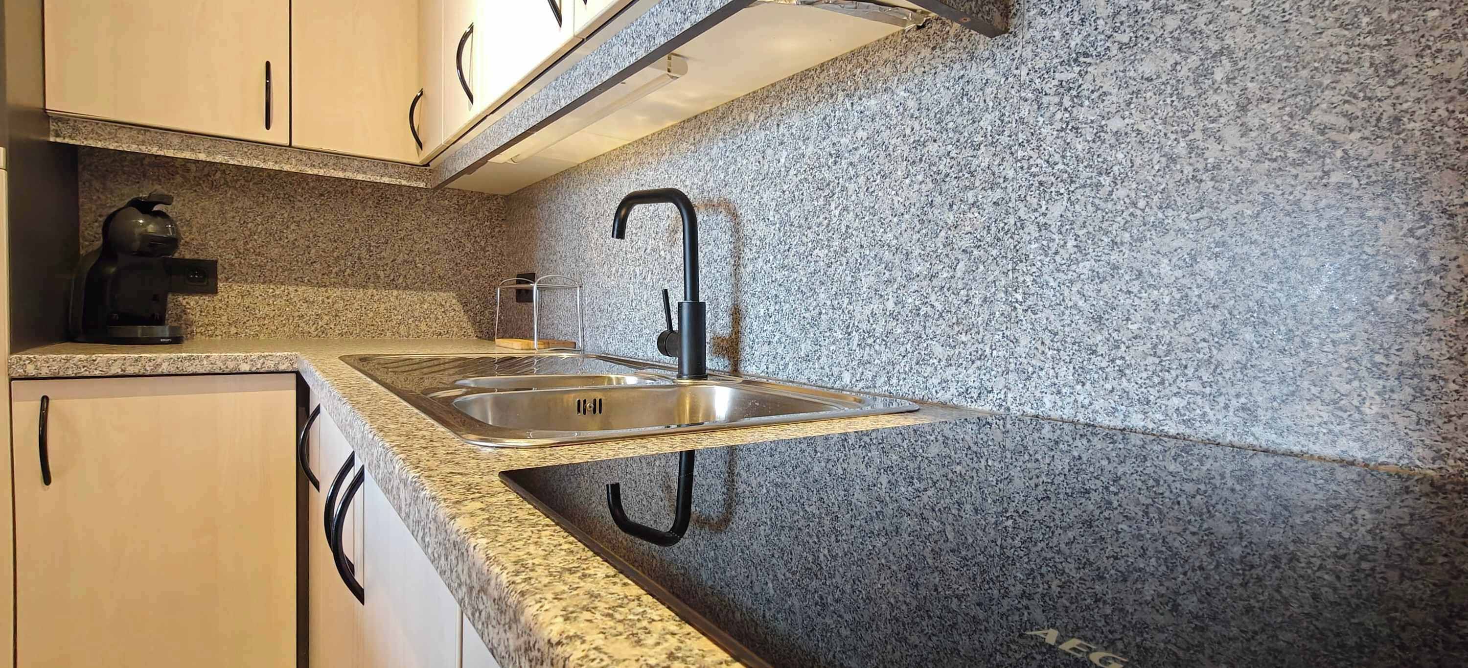 Eine Küche mit Granit-Arbeitsplatten, einer Edelstahl-Spüle und einer Kaffeemaschine.
