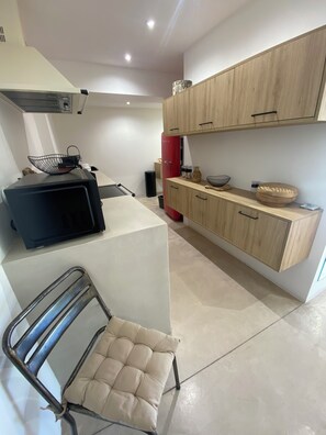 A compact kitchen with a microwave, a red refrigerator, and wooden cabinets.