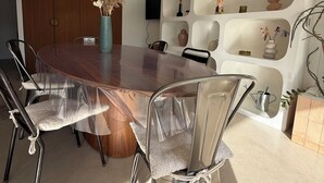Ein moderner Essbereich mit einem runden Tisch, transparenten Stühlen und einer dekorativen Vase.