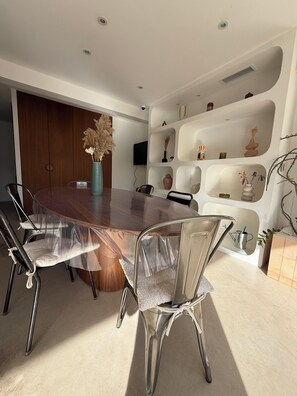 A modern dining area with a round table, clear chairs, and a decorative vase.