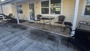 Eine überdachte Terrasse mit Tisch und Stühlen, eine Glastür zum Verschieben und die Zahl '3' an der Wand.