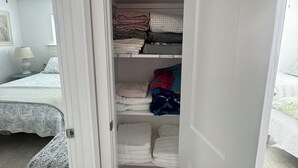 Ein Schlafzimmer mit Bett, Nachttisch, Lampe und Kleiderschrank mit gefalteter Kleidung.