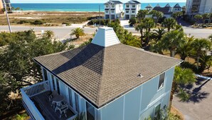 Una casa costera con balcón, vista a la playa y palmeras.