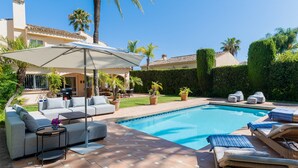 Un jardin avec une piscine, du mobilier d’extérieur et un espace patio.