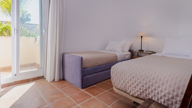 Une chambre d’hôtel comprenant un lit, un canapé-lit, une table de chevet et une fenêtre avec des rideaux.